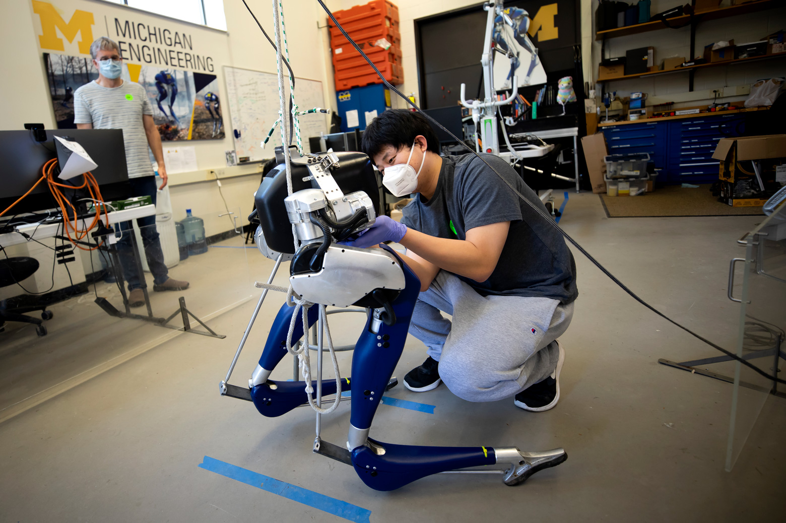 Yukai Gong, Robotics PhD Student, installs a battery into Cassie, a bipedal robot, as Jessy Grizzle, Director of the Robotics Institute, looks on in their lab on North Campus of the University of Michigan in Ann Arbor, MI on May 26, 2020. Photo: Joseph Xu/Michigan Engineering