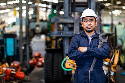 A worker stands with a wrench.   Photo: Adobe
