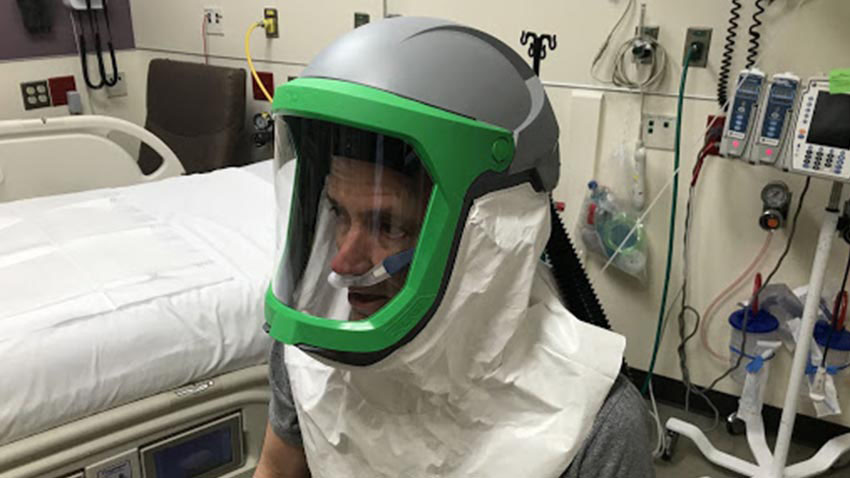 Kevin Ward, M.D., tests the negative pressure helmet system. Preliminary data shows airflows through the hood approach 320 liters/minute, which is more than 20 times greater air exchanges than that produced by a negative pressure room. Credit: MCIRCC