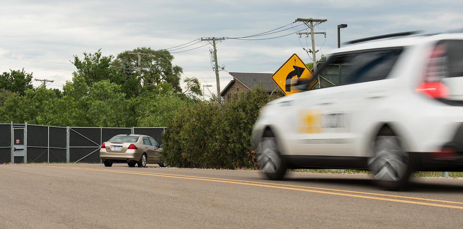 Mcity’s Kia Soul connected and automated vehicle brakes as it approaches a car stopped around a blind curve. Photo by Michigan Photography