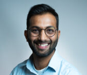 Akshat Gattani wearing a blue shirt and glasses, smiling.