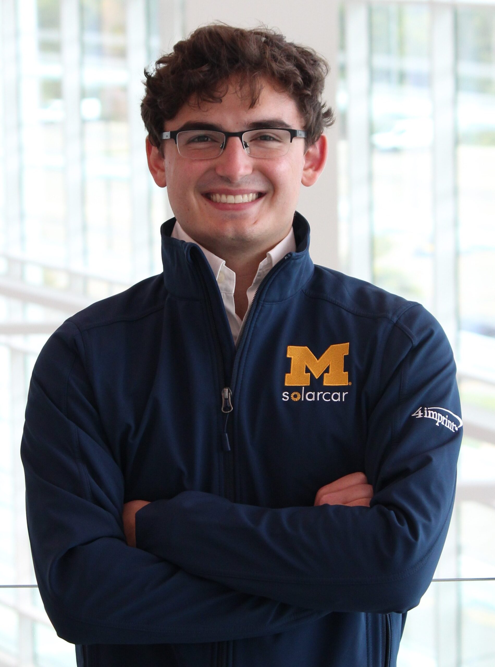 Owen Sayer stands with arms crossed while wearing a Michigan Solar Car Team jacket.